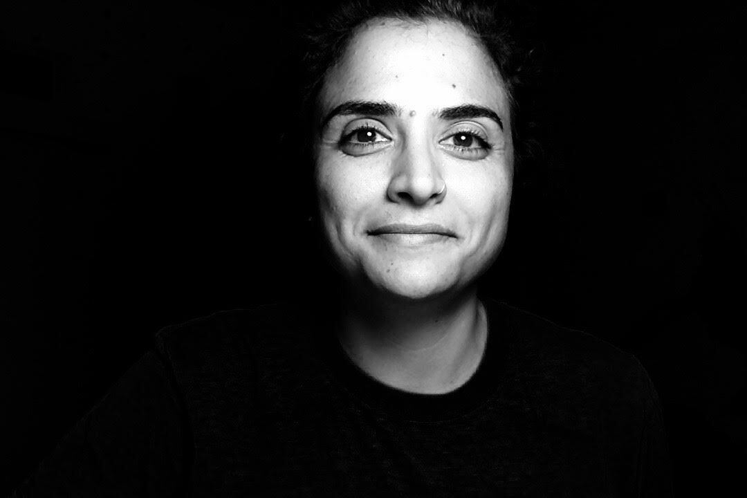 A black and white image of Shadia Qubti a middle eastern woman who is smiling.